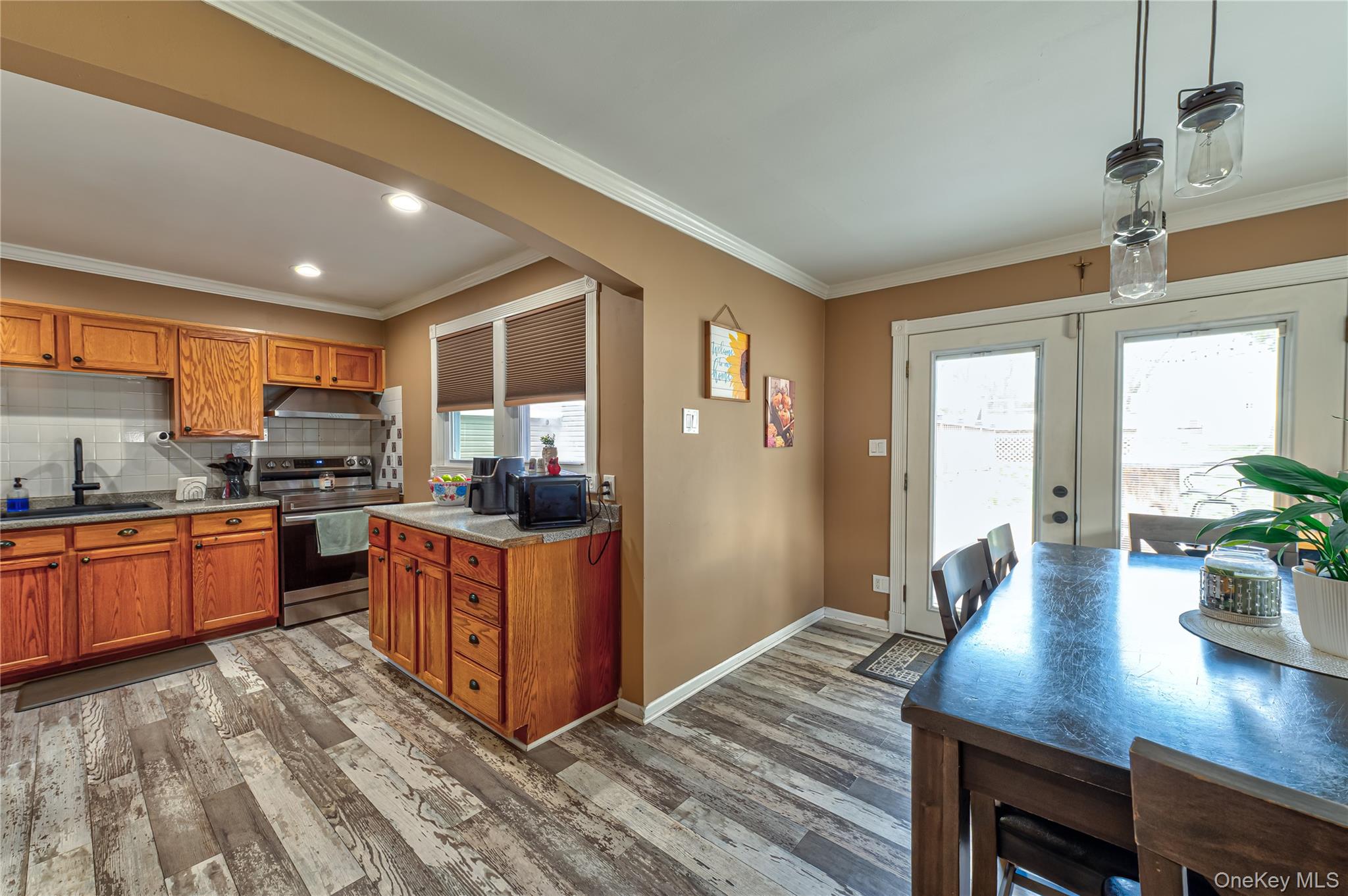 27 Half Mile Road Middle Island, NY 11953 - Photo 9 of 35 Kitchen with crown molding, stainless steel range with electric stovetop, wood finish cabinets, decorative backsplash, and dark wood finished floors