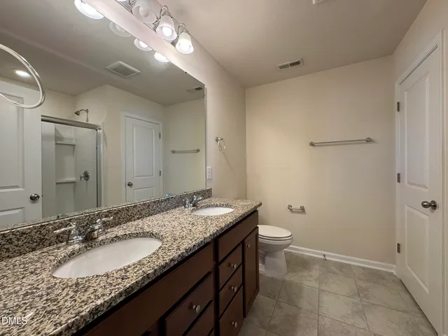 a bathroom with a granite countertop sink a toilet and a mirror