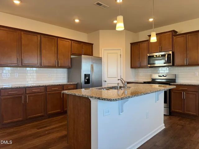 a kitchen with stainless steel appliances granite countertop a sink refrigerator and microwave