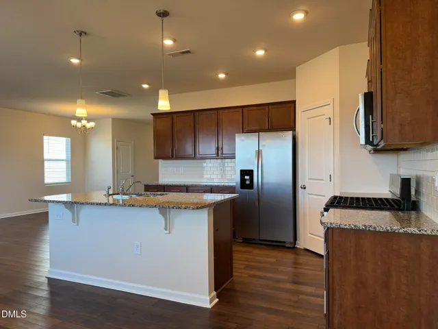 a kitchen with stainless steel appliances granite countertop a sink a stove a refrigerator and a microwave