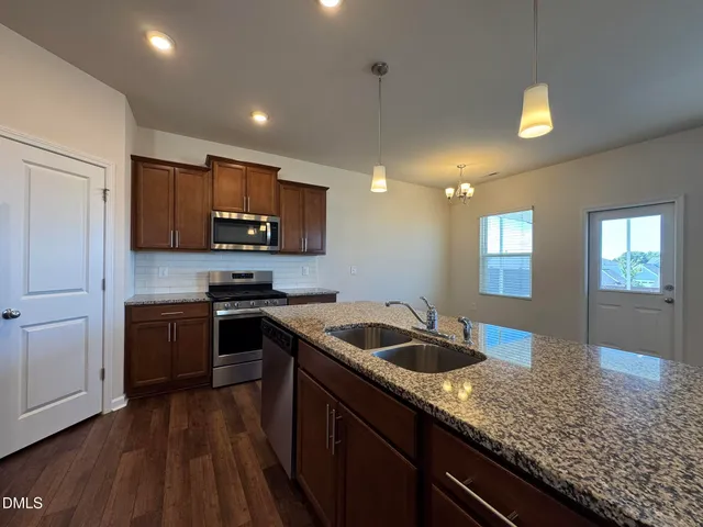 a kitchen with granite countertop a sink a counter space appliances and cabinets