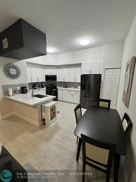 a kitchen with a table chairs refrigerator and microwave