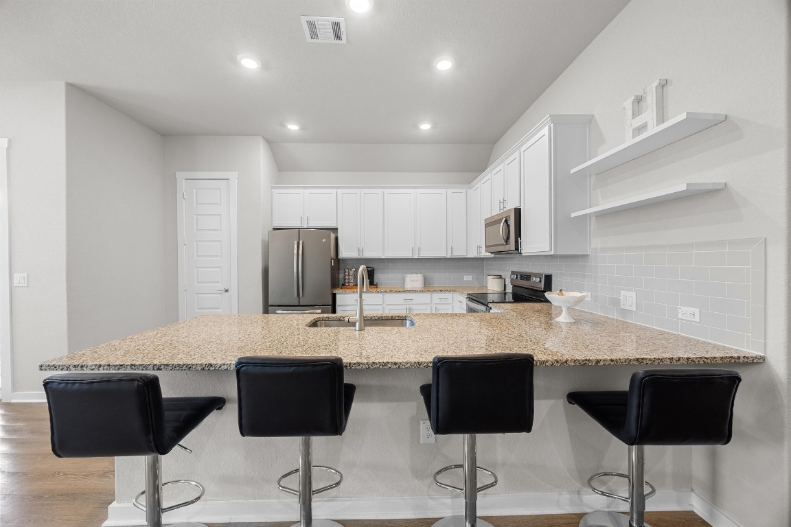401 Peace Pipe Way Georgetown, TX 78628 - Photo 11 of 37 a kitchen with granite countertop white cabinets and black appliances