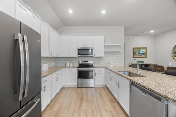a kitchen with granite countertop white cabinets and black appliances