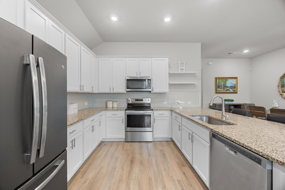 401 Peace Pipe Way Georgetown, TX 78628 - Photo 12 of 37 a kitchen with granite countertop a refrigerator sink and wooden cabinets
