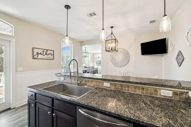 a kitchen with stainless steel appliances granite countertop a dining table chairs and a microwave