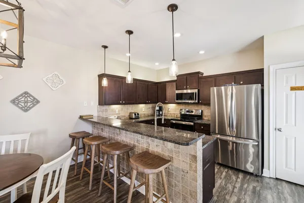 a kitchen with stainless steel appliances granite countertop a sink a oven and a wooden cabinets