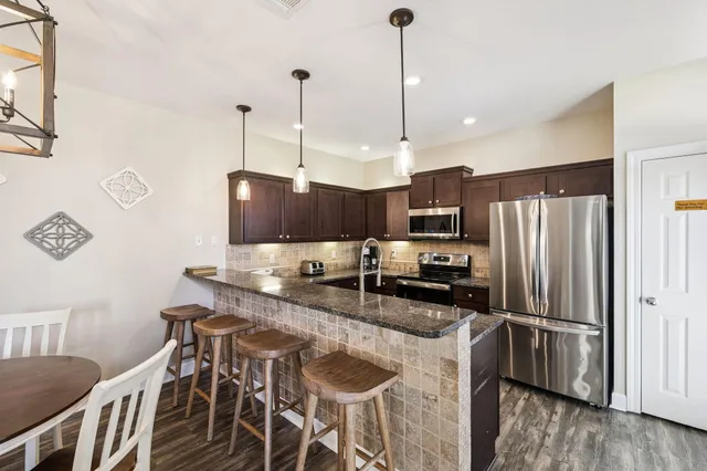 a kitchen with stainless steel appliances granite countertop a sink a oven and a wooden cabinets