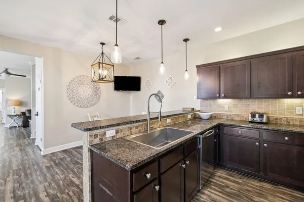 a kitchen with stainless steel appliances granite countertop a sink a stove top oven and wooden cabinets