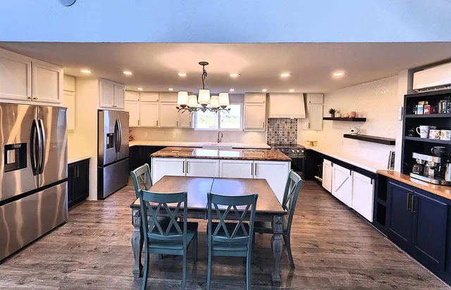 a kitchen with stainless steel appliances a dining table chairs and a refrigerator