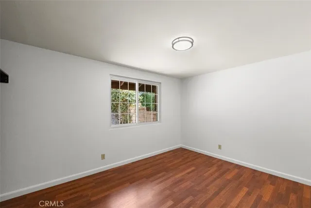 an empty room with wooden floor and window