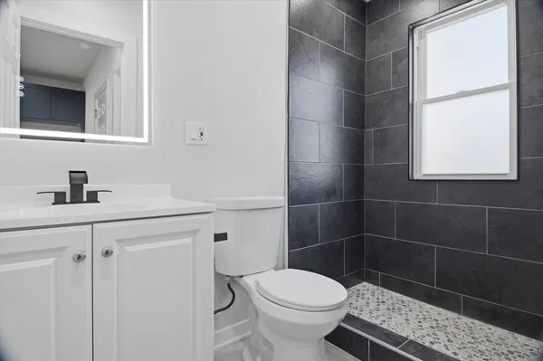 a bathroom with a toilet a sink a window and mirror