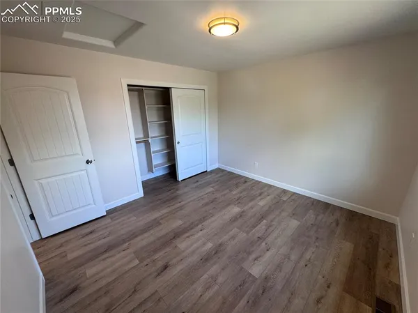 a view of an empty room with wooden floor and closet