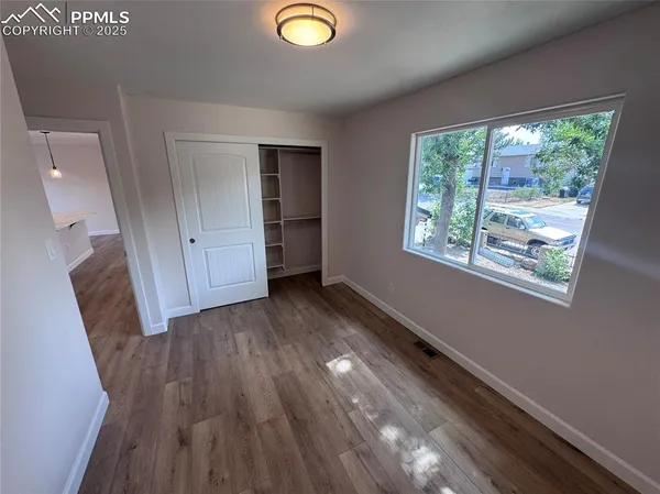a view of empty room with wooden floor and fan