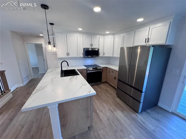a kitchen with stainless steel appliances a refrigerator a sink a stove a microwave and wooden floor
