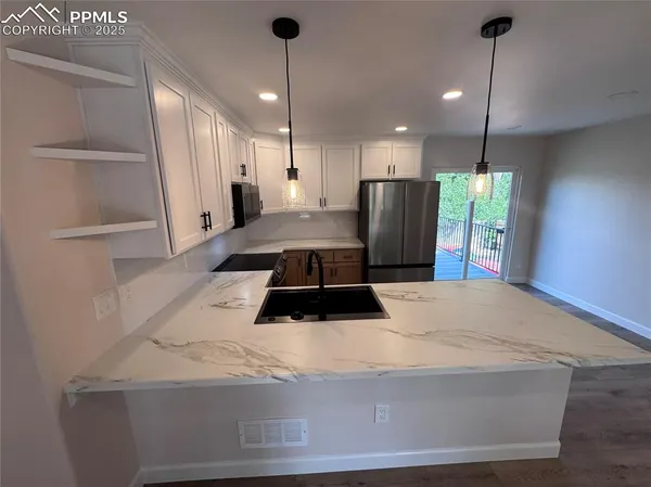 a kitchen with a refrigerator a stove and wooden floor
