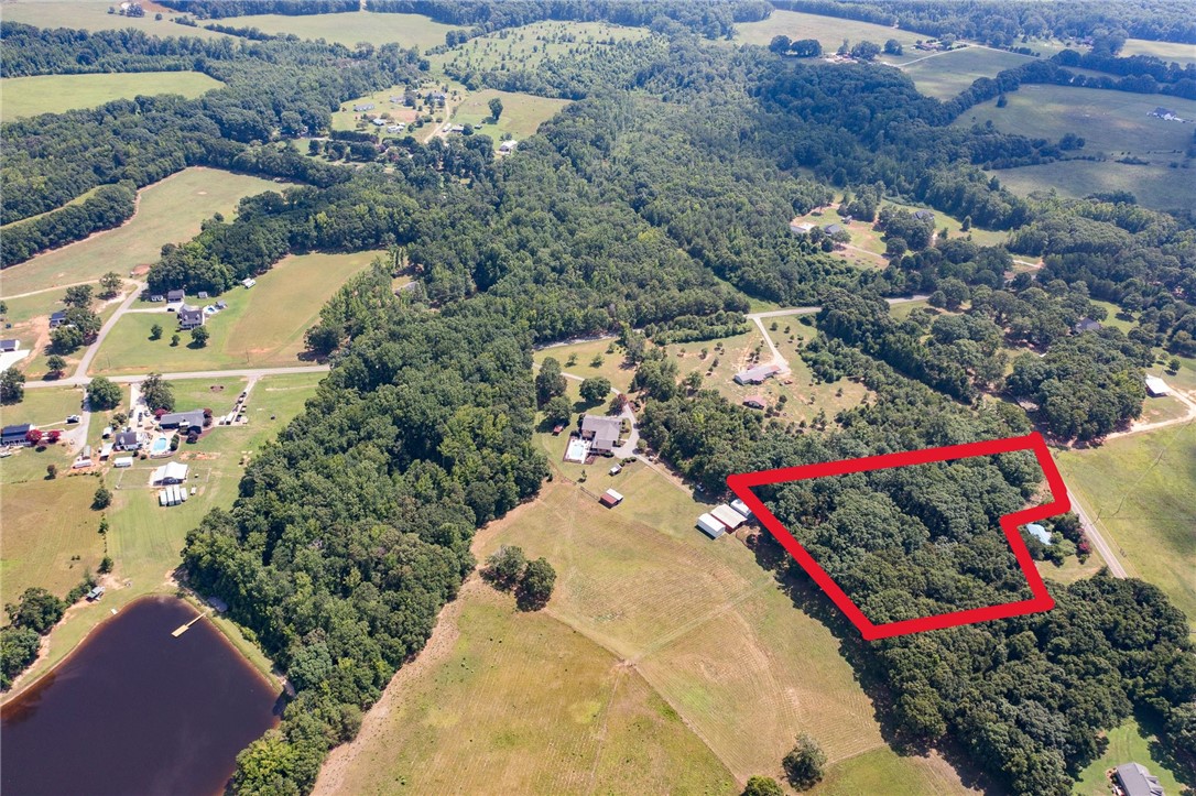 Lot 9 Locke Road Belton, SC 29627 - Photo 1 of 3 An aerial perspective reveals a vast, verdant lot bordered by woodlands and a serene lake.
