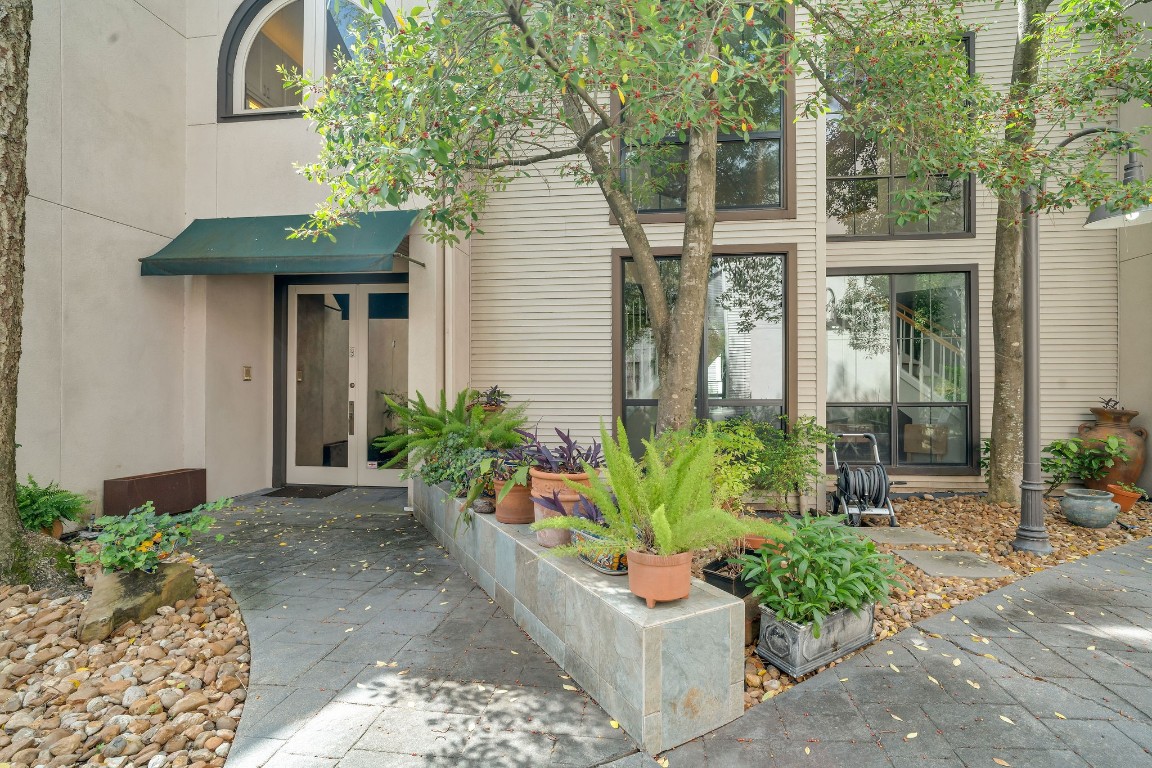 5084 Augusta Street Houston, TX 77007 - Photo 3 of 43 This charming home entrance features a modern exterior with large windows, a welcoming pathway, and lush greenery in planters, creating a serene and inviting atmosphere.