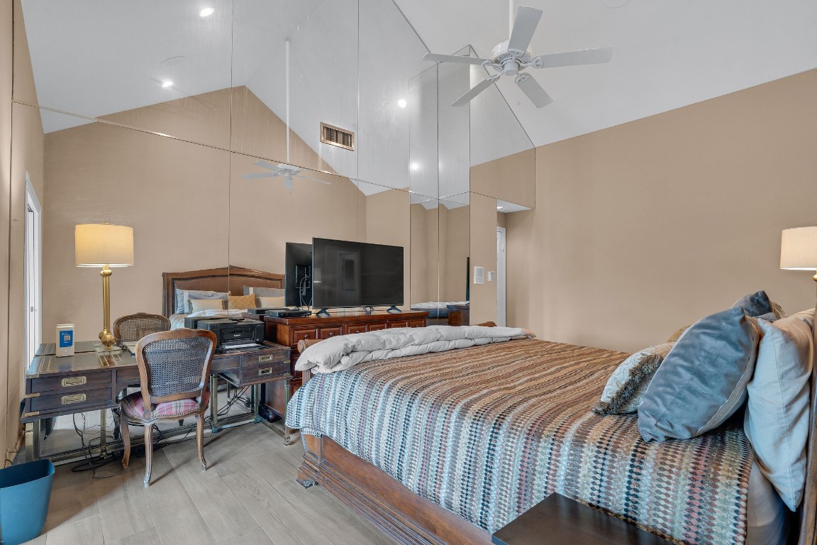 5084 Augusta Street Houston, TX 77007 - Photo 33 of 43 Spacious primary bedroom featuring high vaulted ceilings, and a large mirrored wall.
