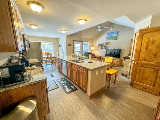 a large white kitchen with a sink a counter top space and stainless steel appliances