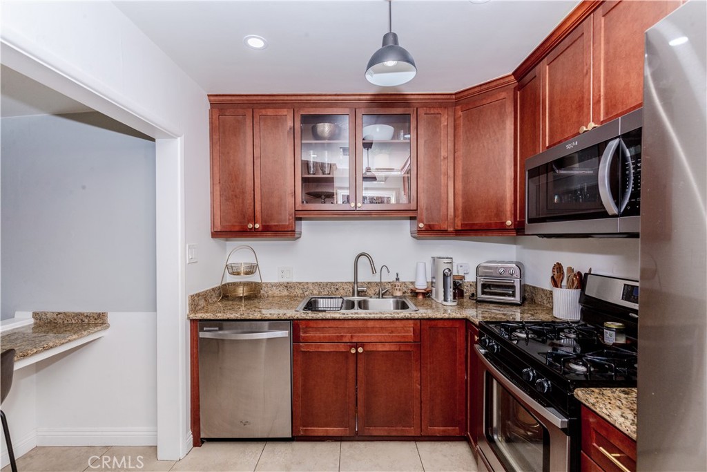 7734 Sycamore Avenue Riverside, CA 92504 - Photo 14 of 47 a kitchen with stainless steel appliances granite countertop wooden cabinets a stove top oven a sink and dishwasher