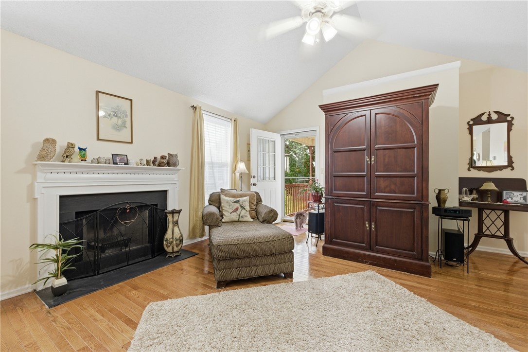 128 Kelly Lane Easley, SC 29642 - Photo 14 of 23 Vaulted ceilings elevate this well-lit living room, featuring a classic fireplace and gleaming hardwood floors.