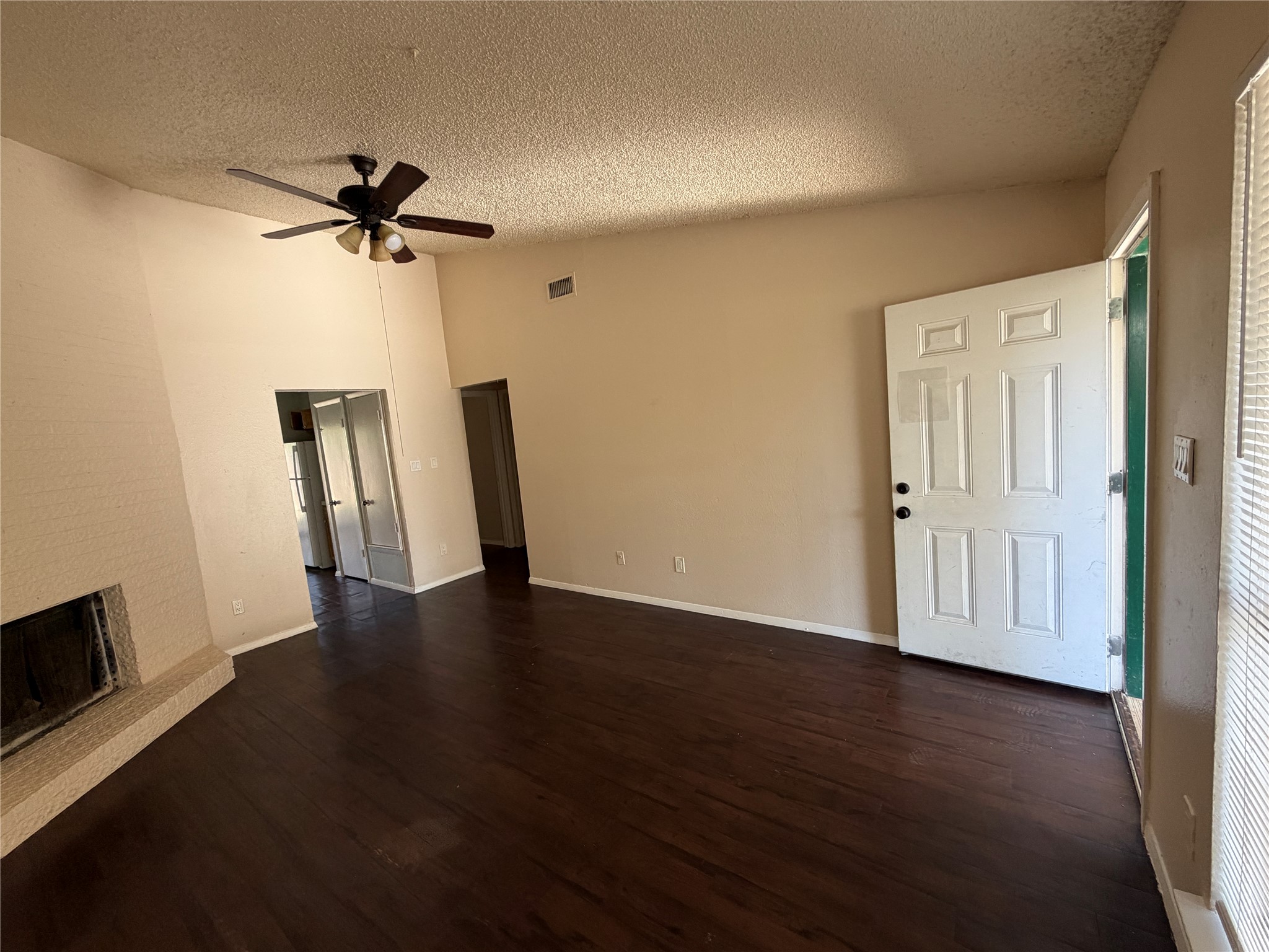 4702 Rocking Chair Road Austin, TX 78744 - Photo 5 of 28 Unfurnished living room featuring dark wood-type flooring, a brick fireplace, and a ceiling fan
