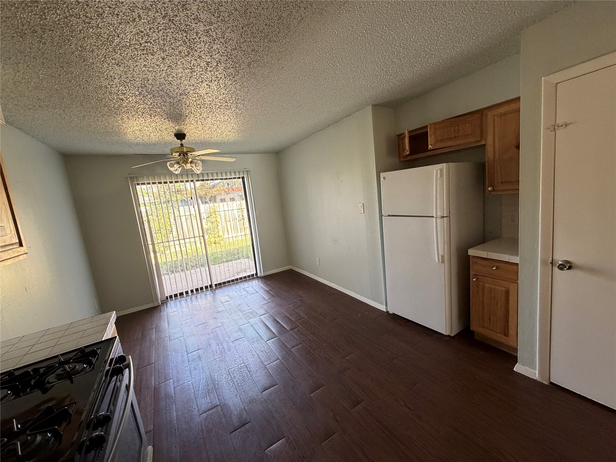 4702 Rocking Chair Road Austin, TX 78744 - Photo 9 of 28 Kitchen featuring black gas range, freestanding refrigerator, dark wood-style floors, a textured ceiling, and wood finish cabinetry