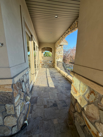 4536 North 475 East Provo, UT 84604 - Photo 48 of 65 Covered outdoor patio featuring extensive natural stone masonry, flagstone flooring, a wrought iron railing, and recessed ceiling lighting