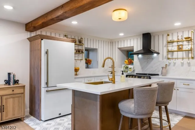 a kitchen with stainless steel appliances granite countertop a sink a stove a refrigerator and island with wooden floor