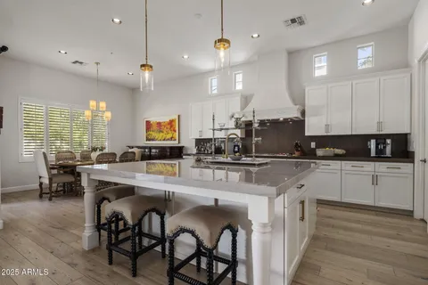 a kitchen with stainless steel appliances kitchen island granite countertop a stove a sink a dining table and chairs with wooden floor