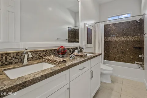 a bathroom with a granite countertop sink mirror vanity and toilet