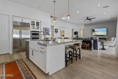 a kitchen with stainless steel appliances kitchen island granite countertop a stove top oven a sink a dining table and chairs with wooden floor