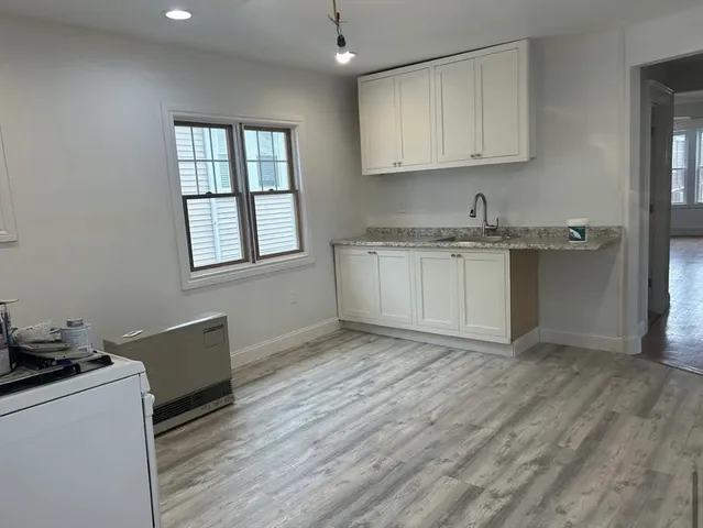a kitchen with granite countertop a sink cabinets and wooden floor