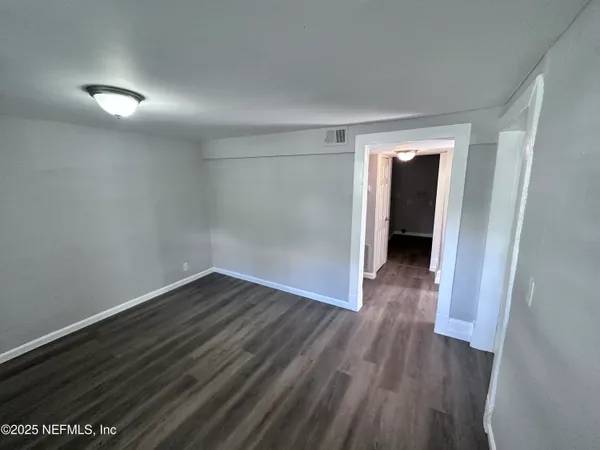 a view of an empty room with wooden floor and closet