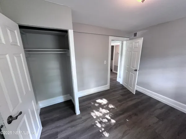 a view of empty room with wooden floor and staircase