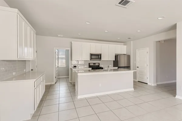 a kitchen with stainless steel appliances a refrigerator sink and white cabinets