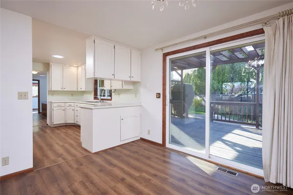 a kitchen with stainless steel appliances granite countertop a refrigerator a sink and white cabinets with wooden floor