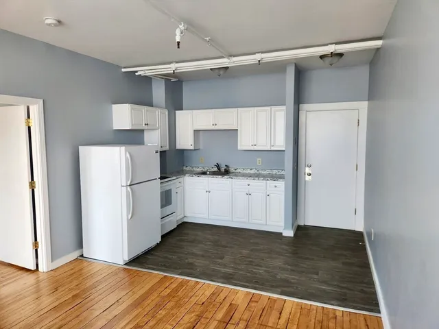 a kitchen with granite countertop a refrigerator and a stove top oven
