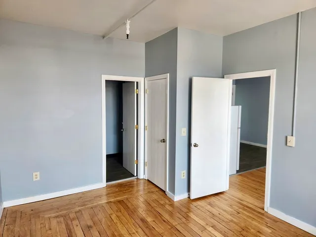 a view of an empty room with closet and wooden floor