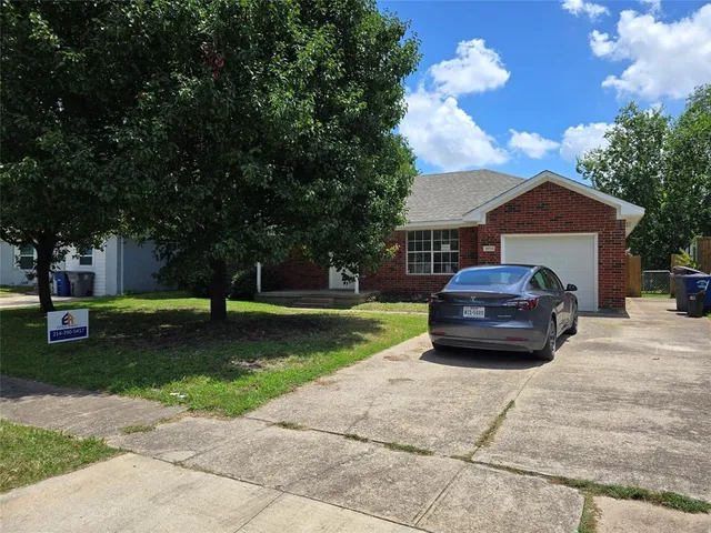 a car parked in front of a house next to a yard