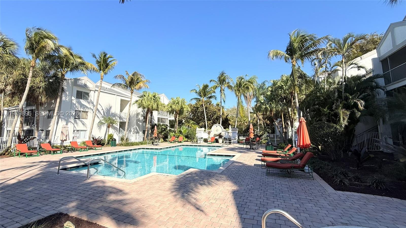 5760 Rock Island Road, Unit 321 Tamarac, FL 33319 - Photo 30 of 36 a view of a swimming pool with a lounge chair and palm trees