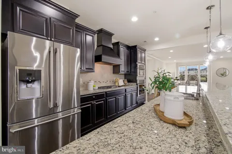 a kitchen with stainless steel appliances granite countertop a refrigerator and a stove top oven