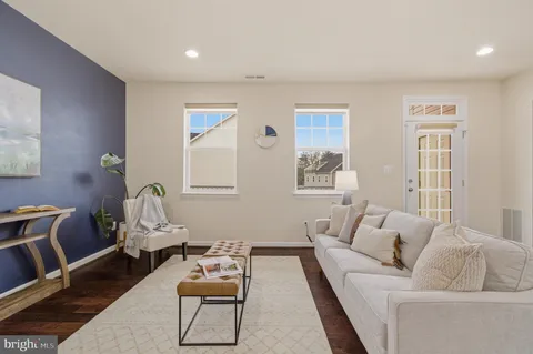 a kitchen with stainless steel appliances kitchen island granite countertop a refrigerator a stove and white cabinets with wooden floor