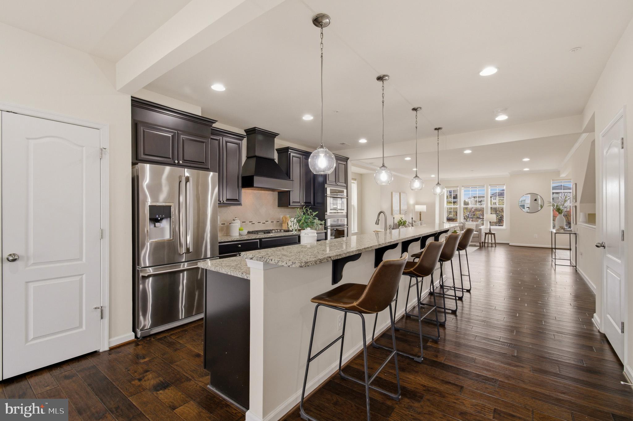 7015 Starwort Way, Unit A Hanover, MD 21076 - Photo 29 of 69 a kitchen with stainless steel appliances kitchen island granite countertop a refrigerator a stove and white cabinets with wooden floor