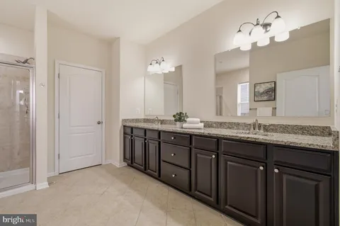 a bathroom with a double vanity sink toilet mirror and shower