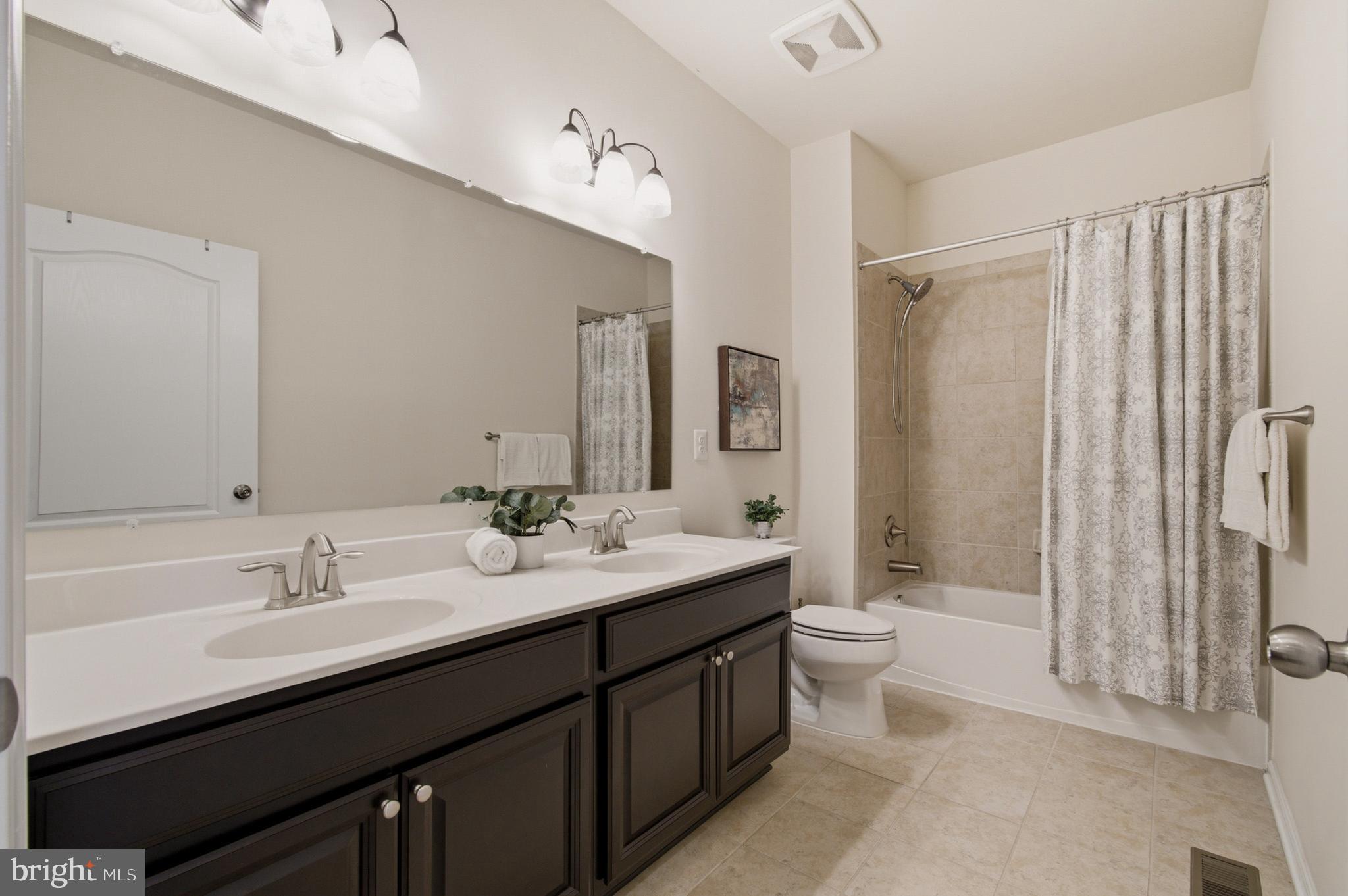 7015 Starwort Way, Unit A Hanover, MD 21076 - Photo 51 of 69 a bathroom with a double vanity sink toilet mirror and shower
