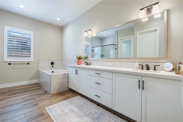a spacious bathroom with double sink a mirror and a bathtub