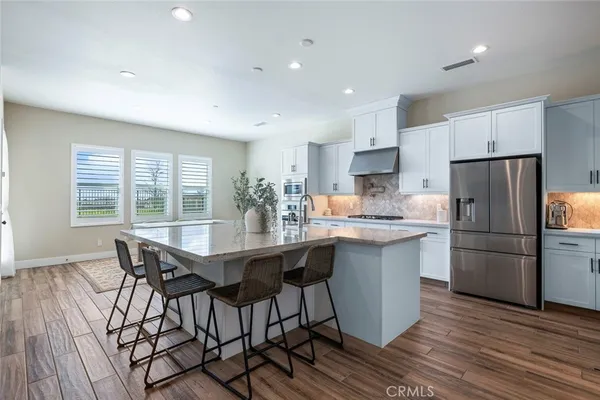 a kitchen with stainless steel appliances a dining table chairs refrigerator microwave and cabinets