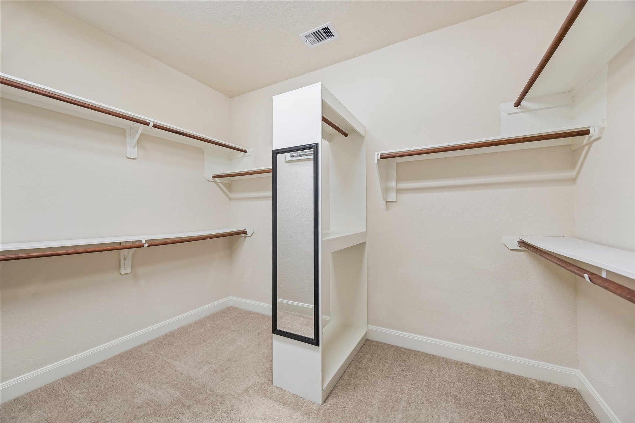 2214 Wembley Way Rosenberg, TX 77471 - Photo 29 of 35 Walk-in closet featuring extensive built-in shelving, multiple hanging rods, a central storage island with shelving, and a full-length mirror